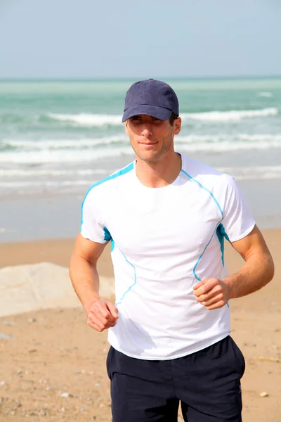Hombre atlético corriendo por el mar en verano — Foto de Stock
