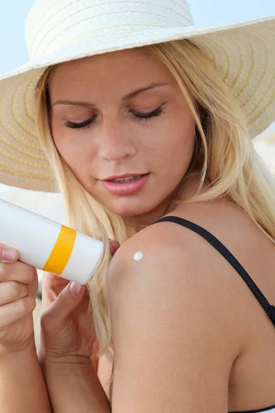 Blond woman putting sunscreen on her shoulder — Stock Photo, Image