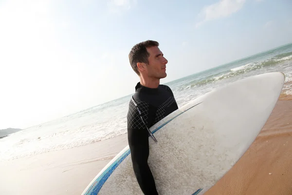 Hombre sosteniendo tabla de surf en la playa — Foto de Stock