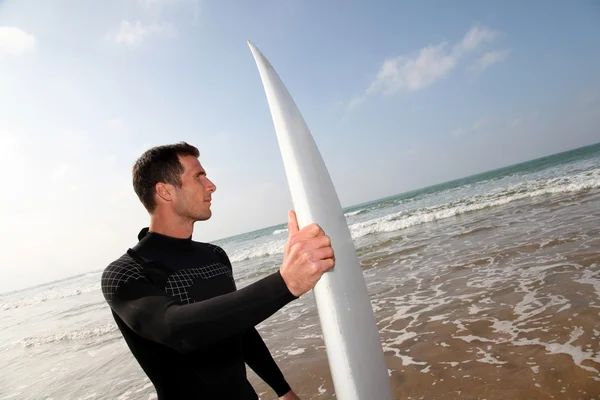 Mężczyzna trzymając deskę surfingową na plaży — Zdjęcie stockowe