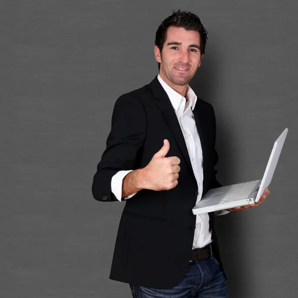 Salesman holding laptop computer and showing thumb up — Stock Photo, Image