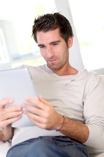 Homem relaxante em casa com tablet eletrônico — Fotografia de Stock