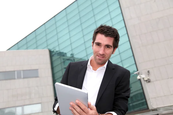 Людина використовує електронний планшет перед сучасною будівлею — стокове фото