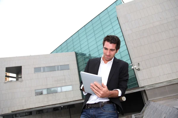 Elektronikus táblagépet használó férfi a modern épület előtt — Stock Fotó