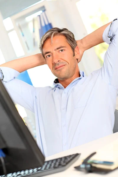 Человек расслабляется в офисе с протянутыми руками — стоковое фото