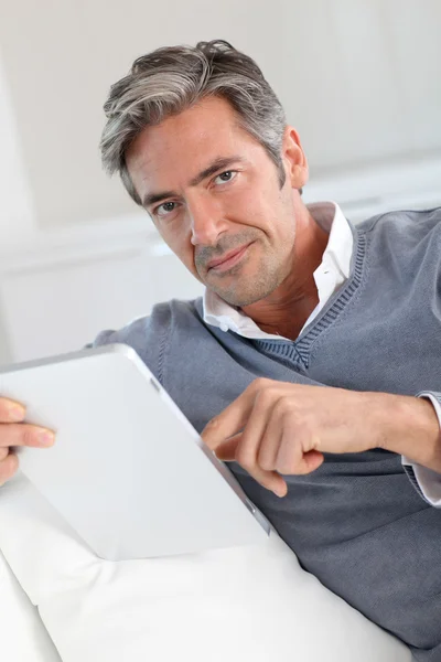 Homem de 40 anos em casa usando tablet eletrônico — Fotografia de Stock