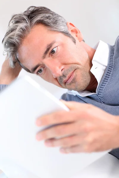 Homem de 40 anos em casa usando tablet eletrônico — Fotografia de Stock