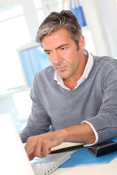 Чоловік сидить в офісі перед ноутбуком — стокове фото