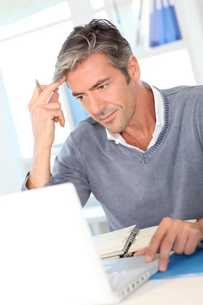 Człowiek siedzi w biurze przed laptopem — Zdjęcie stockowe