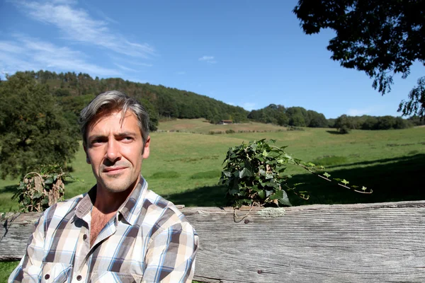 Portrait of handsome breeder leaning on fence — Stock Photo, Image