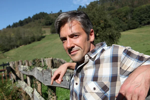 Retrato del apuesto criador apoyado en la valla — Foto de Stock