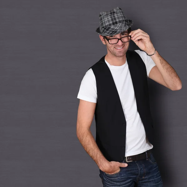 Man with hat and eyeglasses standing on dark background — Stock Photo, Image