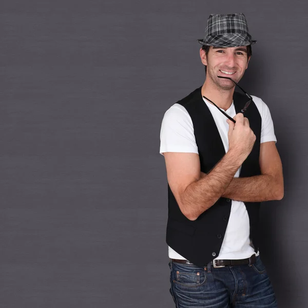 Man with hat and eyeglasses standing on dark background — Stock Photo, Image