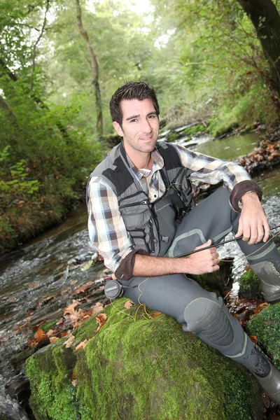 Fisherman sitting by river — Stock Photo, Image