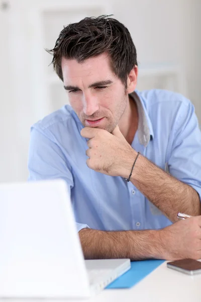 Office worker with thoughtful look in front of laptop — Stock Photo, Image