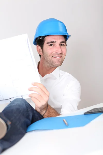 Relaxed architect in office with construction plan — Stock Photo, Image