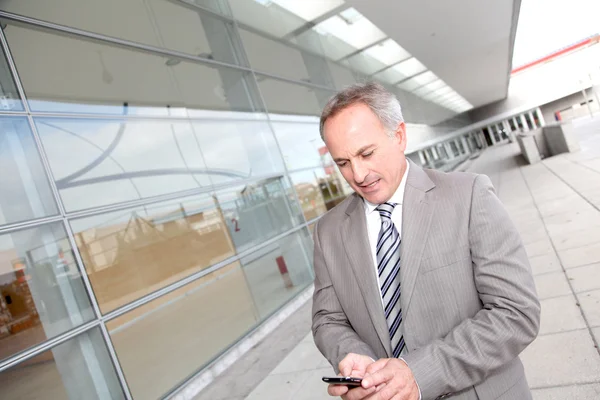 Businessman with mobile phone in front of modern building Stock Picture