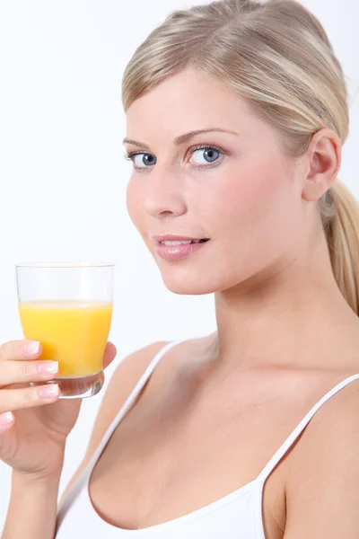 Όμορφη ξανθιά γυναίκα που κρατά ποτήρι χυμό πορτοκαλιού Εικόνα Αρχείου