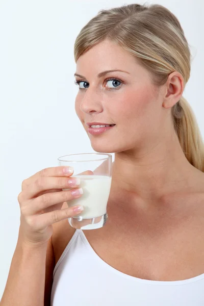 Beautiful blond woman holding glass of milk Royalty Free Stock Images