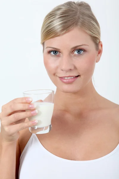 Beautiful blond woman holding glass of milk Royalty Free Stock Photos