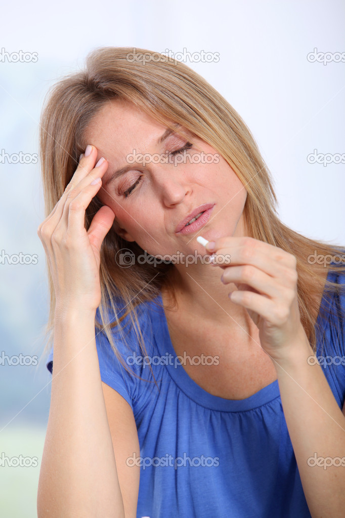 Woman taking pills to ease migraine