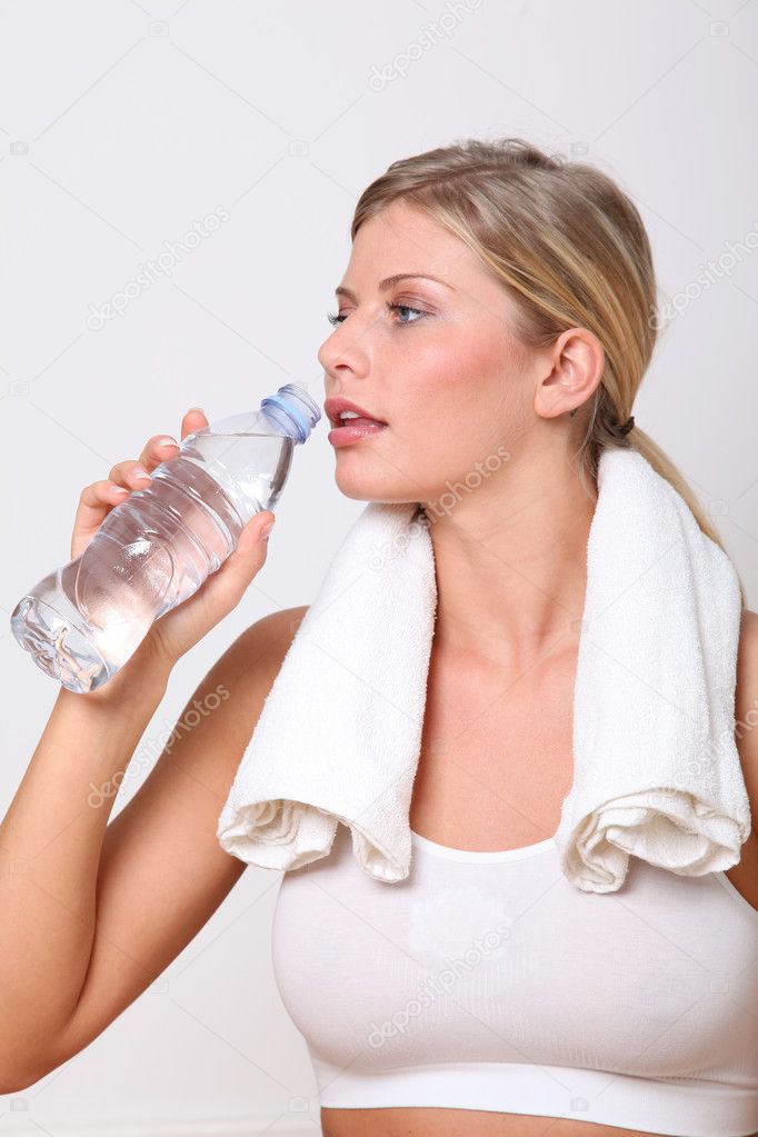 Blond woman drinking water after exercising