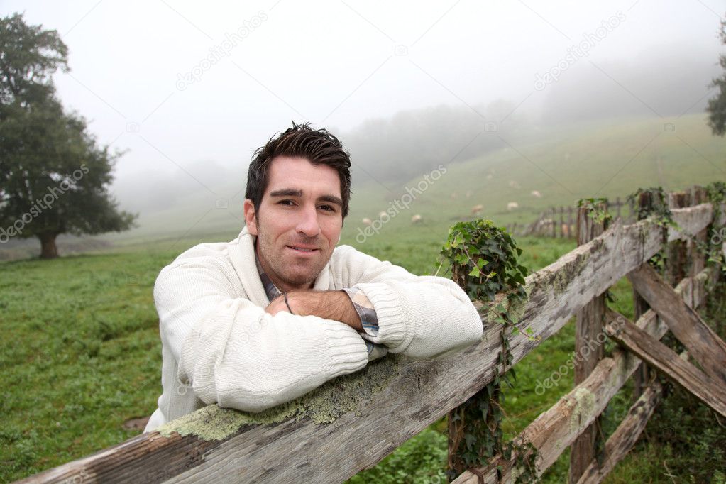 Portrait of breeder leaning on fence