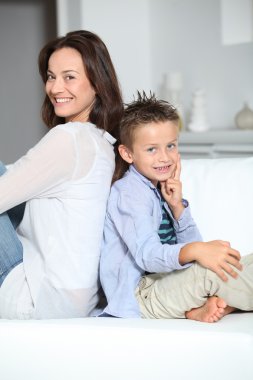 Annemle kanepede oturan sarışın çocuk