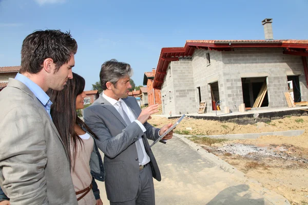 Agente immobiliare che mostra casa in costruzione per coppia — Foto Stock