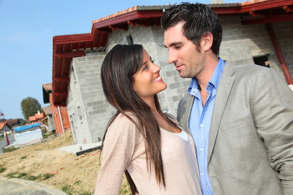 Lyckliga par stående framför hus under uppbyggnad — Stockfoto