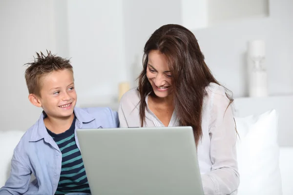Little boy and mother sitting on sofa at home with laptop — Stock Photo, Image