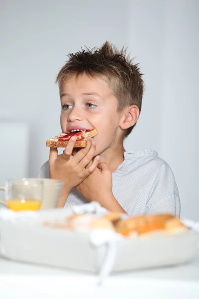 Menino loiro comendo fatia de pão — Fotografia de Stock