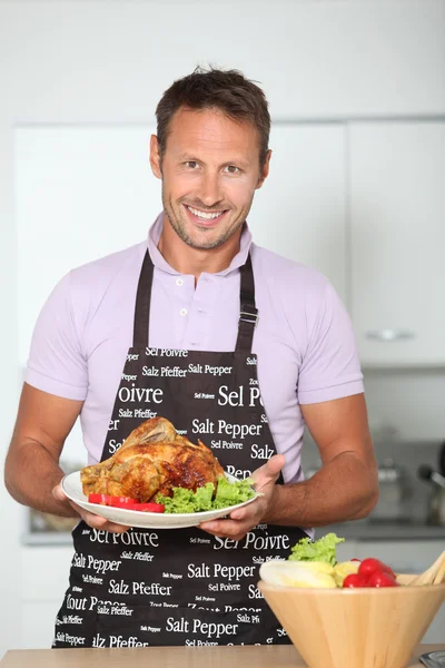 Man in kitchen with apron cooking chicken — Stock Photo, Image