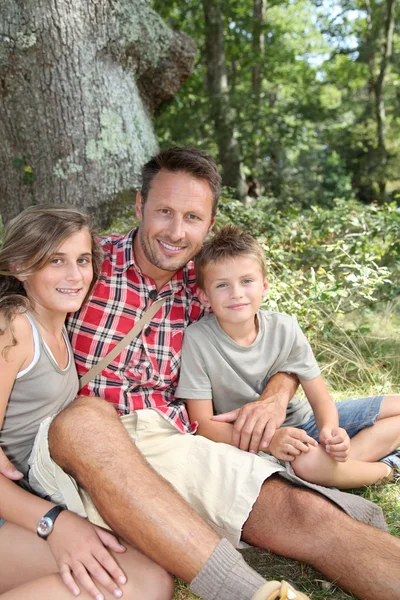 Vater sitzt mit seinen Kindern an einem Baum — Stockfoto