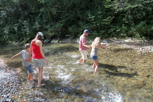 Familia cruzando un río — Foto de Stock