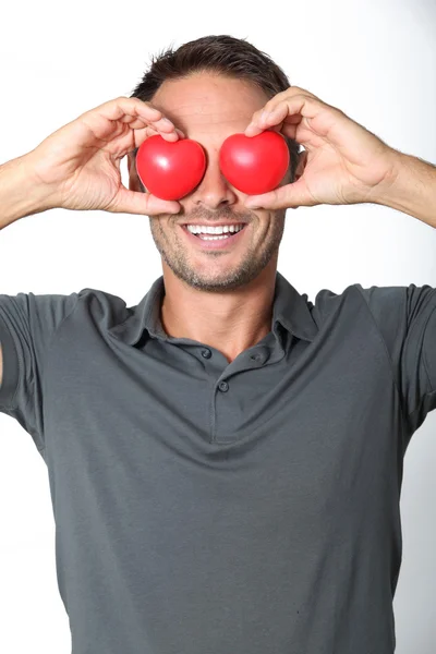 Homem cobrindo seus olhos com 2 corações — Fotografia de Stock