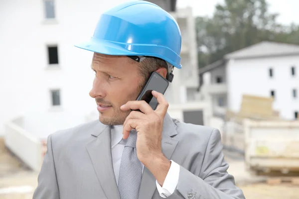 Empresário com capacete verificando local em construção — Fotografia de Stock