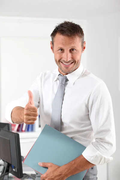 Glad affärsman med tummen upp på kontoret — Stockfoto