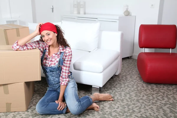 Vrouw zittend op de vloer van de woonkamer naast vakken — Stockfoto