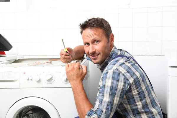 Tesisatçı bozuk çamaşır makinesini tamir ediyor. — Stok fotoğraf