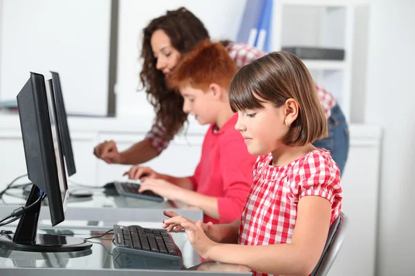 Professor e crianças aprendendo a usar o computador — Fotografia de Stock