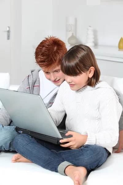 Ung pojke och flicka hemma med laptop — Stockfoto