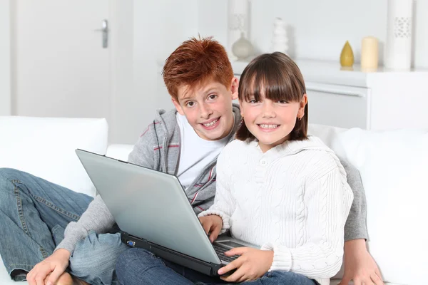 Niño y niña en casa con ordenador portátil — Foto de Stock