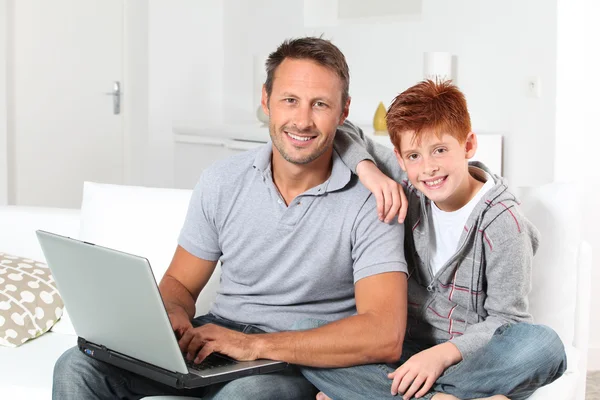 Man och barn hemma med bärbar dator — Stockfoto