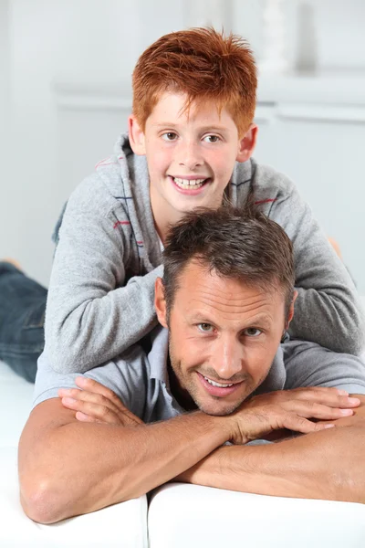 Man met kind liggen op een sofa thuis — Stockfoto