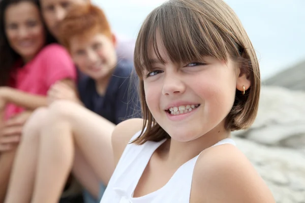 Little girl looking at camera and family in background — Stock Photo, Image