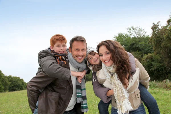Parents doing piggyback to their children in countryside — Stock Photo, Image