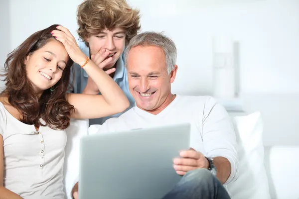 :familjen hemma med bärbar dator — Stockfoto