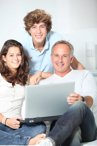 :familjen hemma med bärbar dator — Stockfoto