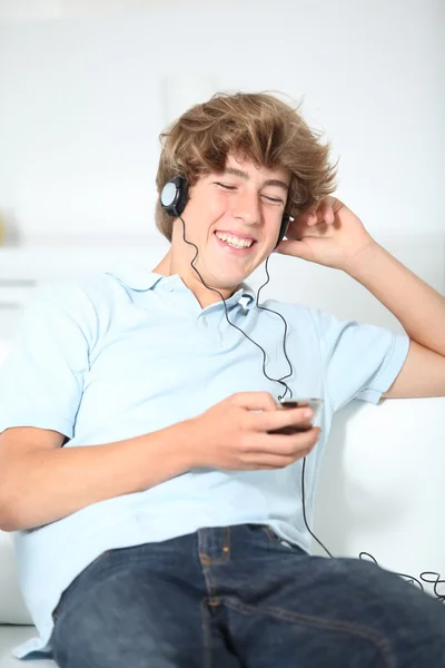 Підліток тягнеться до музики в дивані — стокове фото